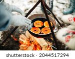 From above traditional mulled wine with slices of orange preparing in pot over burning logs in winter in countryside
