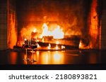 Small photo of Burning fireplace, close up. Cozy atmosphere autumn or winter evening. Open fire with real flames, firewood burning in fireplace with two glasses of red wine