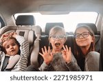 Small photo of Three cute sisters of different ages are riding in the back seat of a car. Girls scream, indulge and laugh. Road trip with three children. Kids having fun in the automobile. Free space for the text.