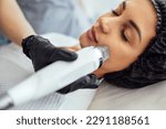Small photo of Microneedle RF lifting procedure. Hardware cosmetology. Beautician conducts a facial rejuvenation procedure for a brunette woman