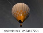 Hot air balloon with bright burning flame flying in the night.