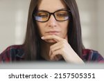 Focused Ukrainian woman in glasses working on laptop. Young programmer female doing work on notebook. Stock photo of white female person works on personal computer. Royalty free image of free lancer 