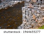 Small photo of Gabion and rock armour - coast and waterways protection. Bridge support constructed using steel wire mesh basket. Stone wall, gabion revetment - protection from backshore erosion