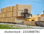 Small photo of Forklift loading lumber wood boards in stack, finished product warehouse ready for transportation. Sawn boards stack in row. Worker on loader stack in row wooden boards at sawmill