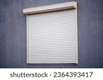 Rolling shutters, window with closed roller shutters. House facade with window on first floor, security and protection concept