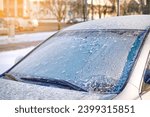 Small photo of Windshield covered with ice, frozen glass and wiper. Car window under layer of ice. Frost on car glass. Low visibility, dangerous driving in winter season.