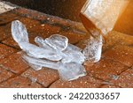 Small photo of Drain pipe and melting ice, wet sidewalk. Ice in drainpipe, icy dam. Downpipe on residential building with melting ice. Drainpipe and ice on paving slabs. Spring thaw, Selective focus