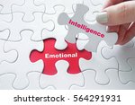 Close up of girl's hand placing the last jigsaw puzzle piece with word Emotional Intelligence