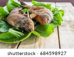 Small photo of The smoked baked fish is laid out on green leaves lying on coarse unglued boards. Home healthy eating at a picnic