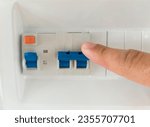 Finger pressing the lever of residual current operated circuit breaker. Selective focus