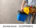 Worker man holding construction helmet tool and toolbox near concrete or cement wall. Male hand and hard hat for house room renovation. Home renovation concept