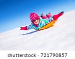 little girl riding on snow slides in winter time