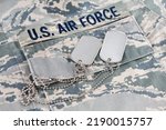 Small photo of US AIR FORCE branch tape and veteran old type dog tags on digital tiger-stripe pattern Airman Battle Uniform background
