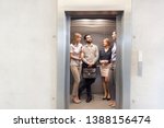Colleagues talking while standing in elevator at office