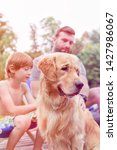 Small photo of Man and boy stroking Golden retriever on pier during summer weekend