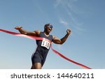 Low angle view of an African American male runner winning race against blue sky