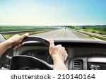 Man's hands of a driver on steering wheel of a minivan car on asphalt road