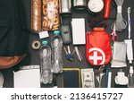 Small photo of Emergency backpack equipment organized on the table. Documents, water,food, first aid kit and another items needed to survive.