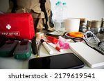 Small photo of Emergency backpack equipment organized on the table. Documents, water,food, first aid kit and another items needed to survive.