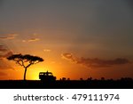 Silhouette of a Safari jeep, tree and Wildebeest during sunset at Masai Mara