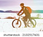 Small photo of Sport cyclist pushing bike in the hardest and snowy landscape during winter. Abstract lighting, colorful flare.