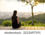 Woman sit on the wooden bench and look at the sunset