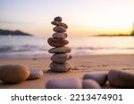 Small photo of Balance pebble stone in the sand beach at sunset