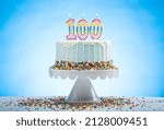 Blue Birthday Cake with Sprinkles on a White Cake Plate and Blue Background with 100 candles on Top