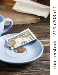 Small photo of Restaurant tips or gratuity, american banknotes and coins on plate