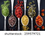 Spoons of various superfoods on black background