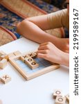 Small photo of Two children are playing Bingo board Tic-tac-toe game. Cozy home. Joy and fun. Play time. Indoor activity. Classes for children of preschool and primary school age. The development of mindfulness.