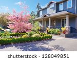 Grey large luxury house  exterior with spring blooming pink trees.