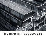 Stacked steel pipes with rectangular cross-section, close-up monochrome photo with selective focus