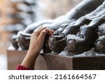Small photo of Hand holding a toe of the Atlas statue, tourist omen to make a wish. Classic architecture of Saint-Petersburg, Russia