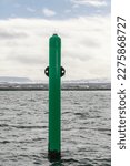 Small photo of Starboard hand green spar buoy with light on top, close up vertical photo. Navigation equipment of Reykjavik harbor, Iceland