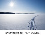 Sun, snow and Ski track crossing a frozen lake. Winter sport - cross-country skiing.