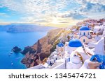 Beautiful Oia town on Santorini island, Greece. Traditional white architecture  and greek orthodox churches with blue domes over the Caldera, Aegean sea. Scenic travel background.