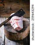 Small photo of Raw cuting veal shank ossobuco with old backsword over piece of wood.