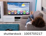 Woman Lying On Sofa Watching Television With Colorful Applications On Screen