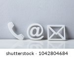Contact Methods. Close-up Of A Phone, Email and Post Icons Leaning On White Wall