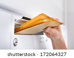 Close-up Of Postman Putting Letters In Mailbox
