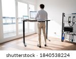 Man Working On Computer At Standing Desk In Home Office 