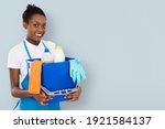 Portrait Of A Smiling African Female Janitor Holding Cleaning Equipment