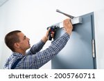 Small photo of Handyman Installing And Fixing Automatic Door Closer. Maintenance And Service