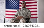 Small photo of Veteran Sitting In Wheelchair In Front Of An American Flag