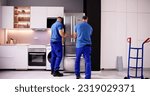 Small photo of Delivery And Install Of Refrigerator Appliance. Mover Carrying Fridge