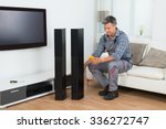 Full length of technician checking TV speaker with multimeter at home