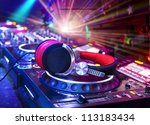 Dj mixer with headphones at nightclub.  In the background laser light show