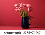 Small photo of Beautiful spring bouquet of pink tulips in a blue decanter on a pink background. Color Viva Magenta 18-1750, in 2023