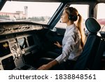 Confident woman pilot flying a commercial aircraft, sitting in cockpit.